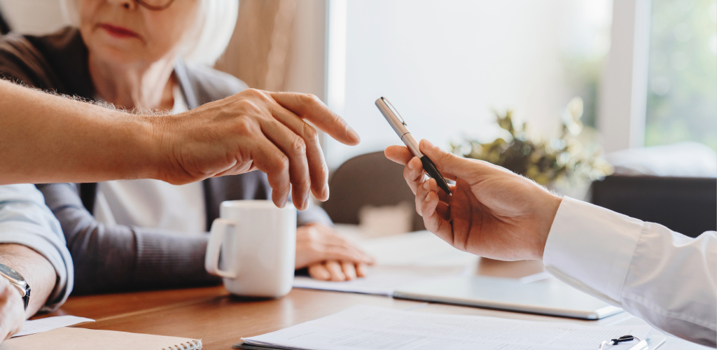 Hände mit Stift über einem Schreibtisch